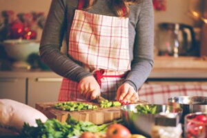 Person chopping vegetables in kitchen surrounded by fresh food items