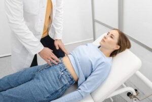 Doctor checking the abdomen of a young girl on clinic